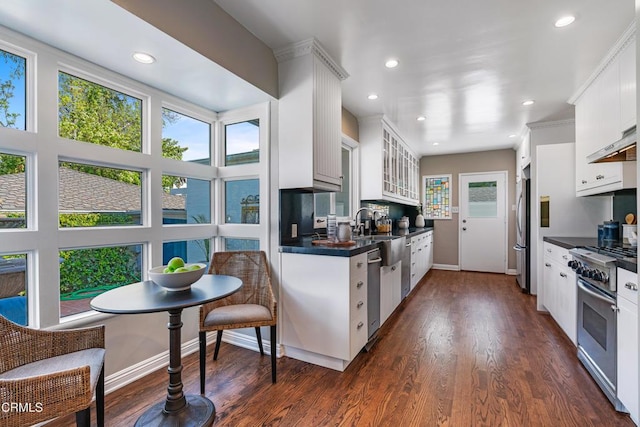 kitchen featuring dark wood-style flooring, glass insert cabinets, white cabinetry, dark countertops, and stainless steel appliances