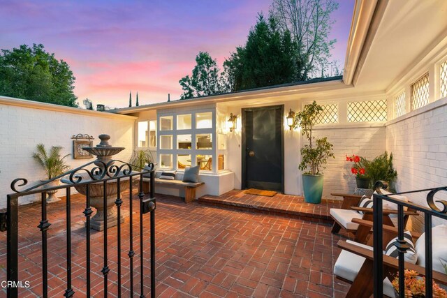 property entrance featuring a patio area and brick siding
