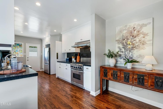 kitchen featuring dark wood finished floors, white cabinetry, under cabinet range hood, dark countertops, and stainless steel appliances