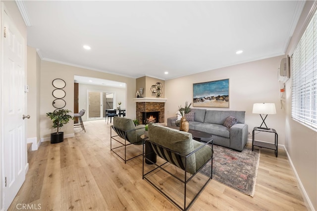 living room with baseboards, a warm lit fireplace, light wood-style floors, crown molding, and recessed lighting
