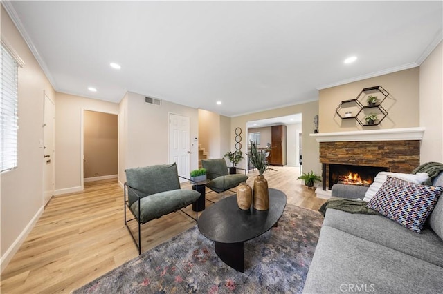 living area featuring visible vents, ornamental molding, a stone fireplace, light wood-type flooring, and stairway