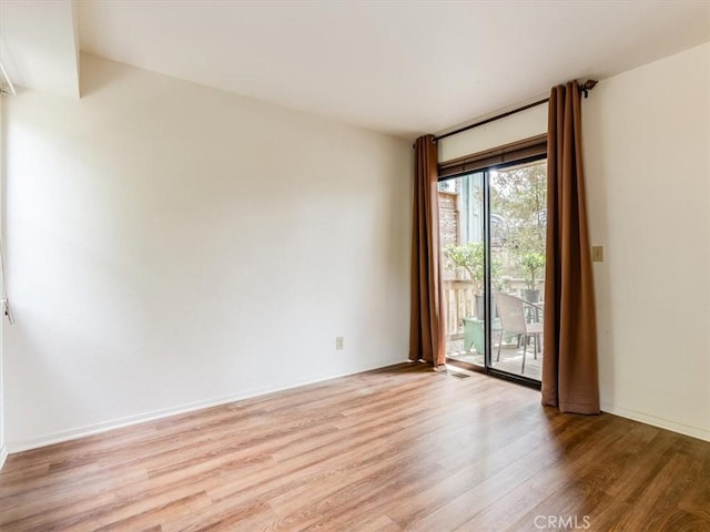 spare room featuring baseboards, visible vents, and light wood-style floors
