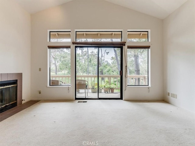 unfurnished living room featuring carpet flooring, visible vents, a wealth of natural light, and a tile fireplace