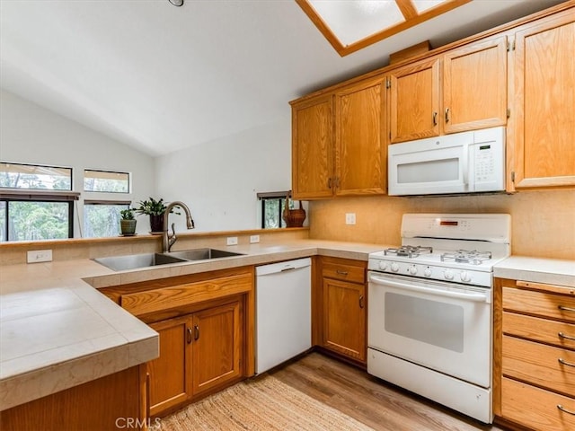 kitchen with a sink, lofted ceiling, white appliances, and light countertops