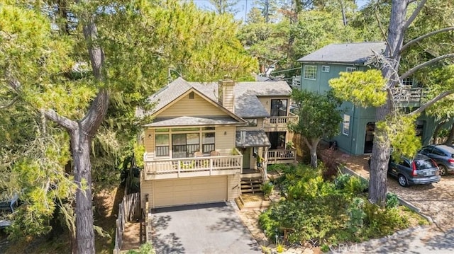 view of front of home with an attached garage, a chimney, roof with shingles, and aphalt driveway