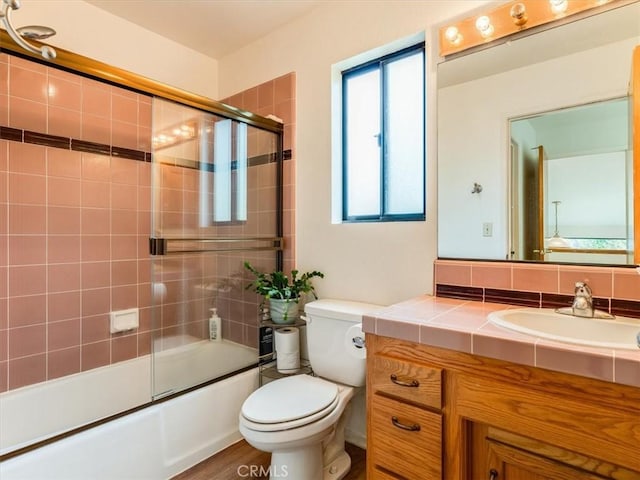bathroom with toilet, shower / bath combination with glass door, and vanity