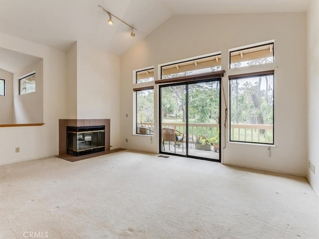 unfurnished living room with carpet flooring, track lighting, and plenty of natural light