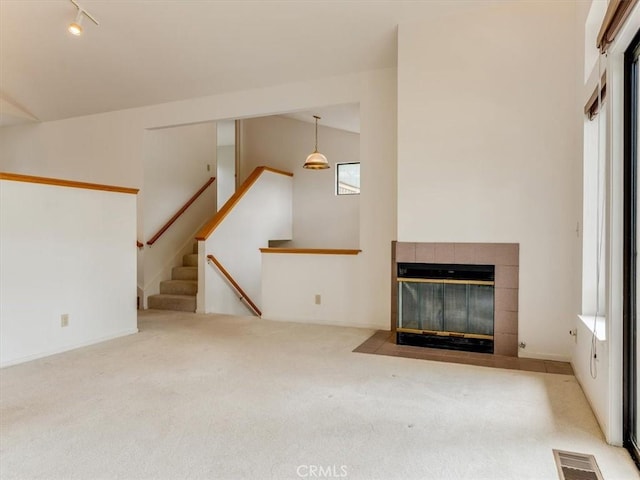 unfurnished living room featuring visible vents, a fireplace, rail lighting, carpet, and stairs