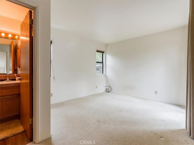 spare room with light colored carpet and a sink