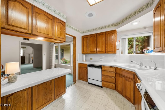 kitchen featuring brown cabinetry, dishwasher, a sink, and tile counters