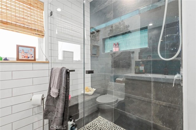 bathroom featuring toilet, tile walls, and a shower stall