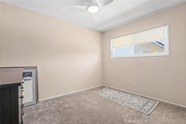 spare room featuring a textured ceiling, ceiling fan, baseboards, and carpet floors