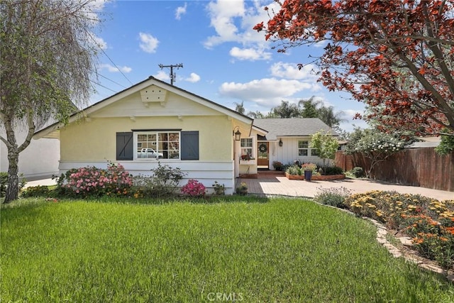 view of front of home with a front yard and fence