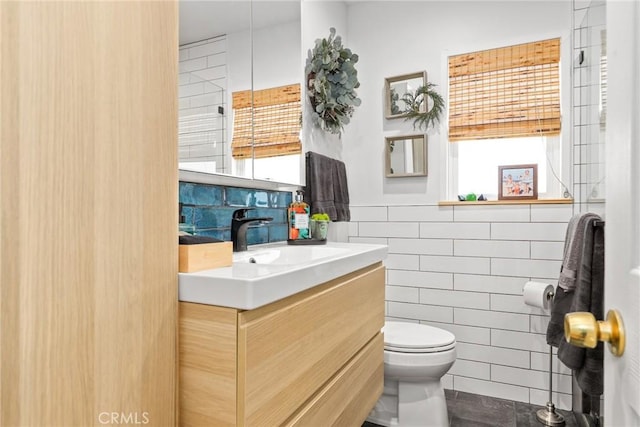 bathroom with toilet, tile walls, vanity, and a wainscoted wall