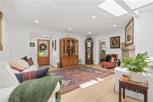 living area featuring recessed lighting, light wood-style floors, baseboards, and a skylight
