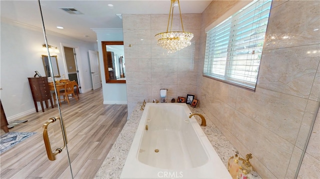 bathroom featuring visible vents, baseboards, an inviting chandelier, crown molding, and a garden tub