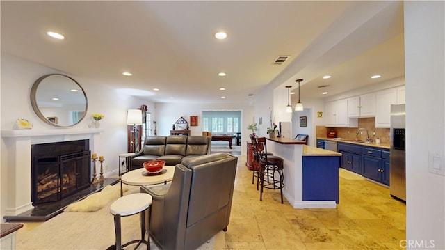living room with visible vents, baseboards, recessed lighting, and a fireplace with raised hearth