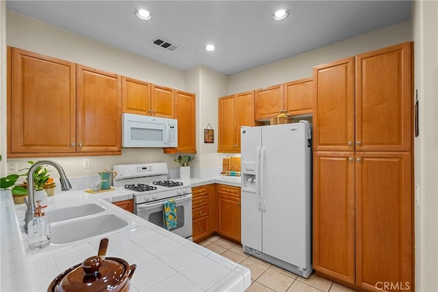 kitchen featuring white appliances, visible vents, recessed lighting, a sink, and tile counters