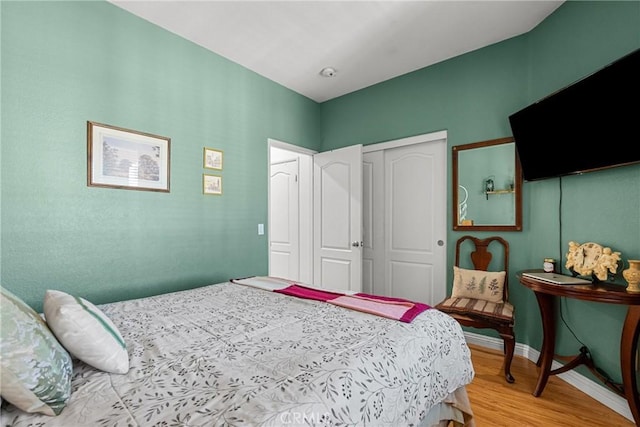 bedroom featuring wood finished floors, a closet, and baseboards