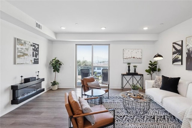 living area featuring baseboards, visible vents, wood finished floors, and recessed lighting