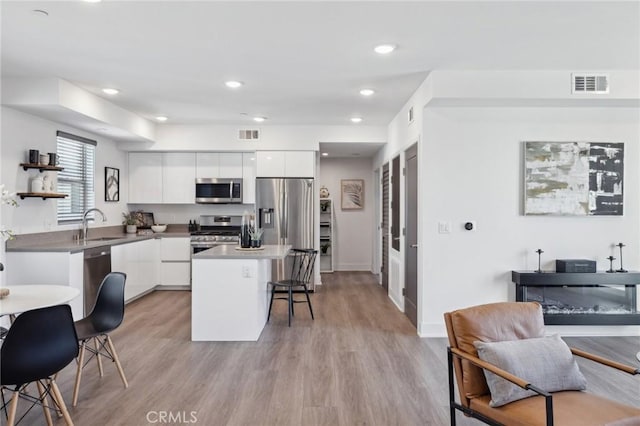 kitchen featuring a breakfast bar area, stainless steel appliances, white cabinets, and modern cabinets