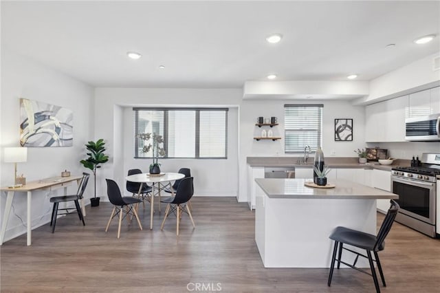 kitchen with a breakfast bar area, white cabinetry, stainless steel appliances, a center island, and recessed lighting