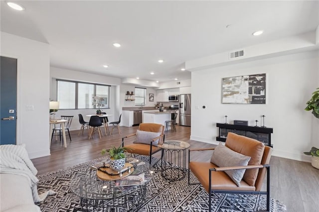 living area featuring baseboards, visible vents, wood finished floors, and recessed lighting