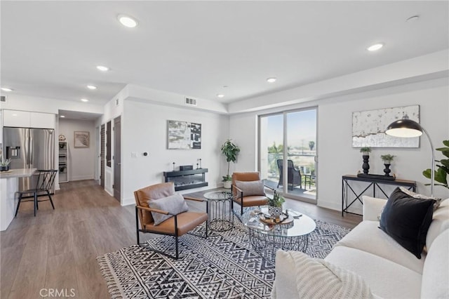 living room with baseboards, visible vents, wood finished floors, and recessed lighting