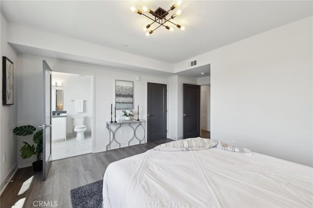 bedroom featuring a chandelier, visible vents, wood finished floors, and ensuite bathroom