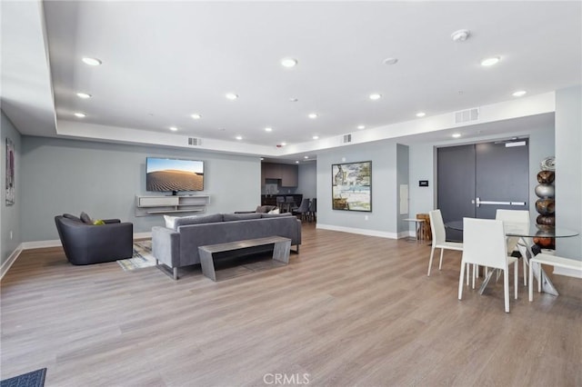 living area with baseboards, visible vents, and light wood-style floors