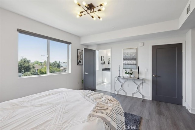 bedroom featuring wood finished floors, a chandelier, ensuite bathroom, and visible vents