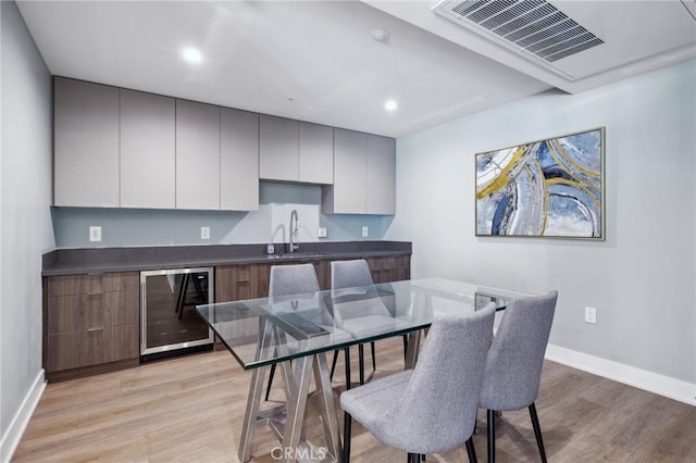 dining space with baseboards, beverage cooler, visible vents, and light wood-style flooring