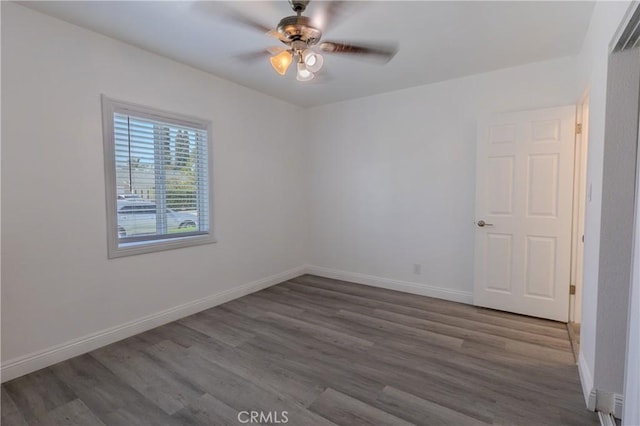 spare room featuring dark wood-type flooring, baseboards, and ceiling fan