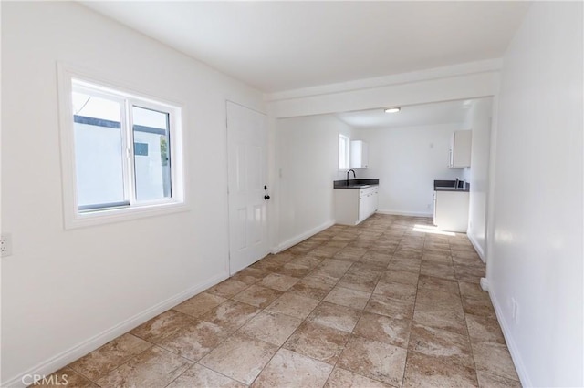 interior space with a sink, baseboards, and plenty of natural light