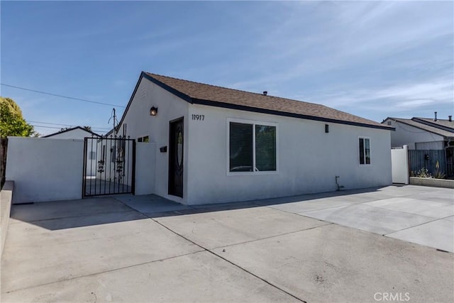 view of front of house with fence, a gate, and stucco siding