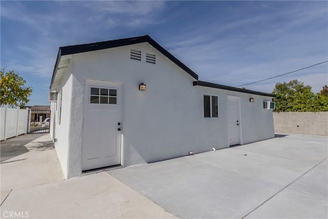 rear view of house featuring a patio area, stucco siding, and fence