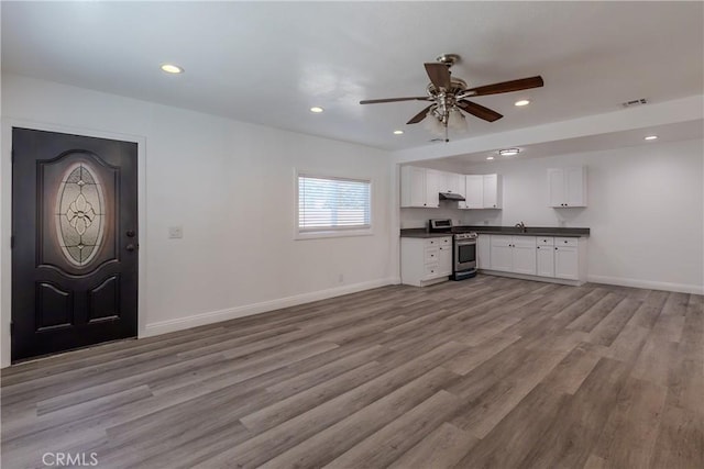 interior space featuring dark countertops, white cabinets, gas range, visible vents, and ceiling fan