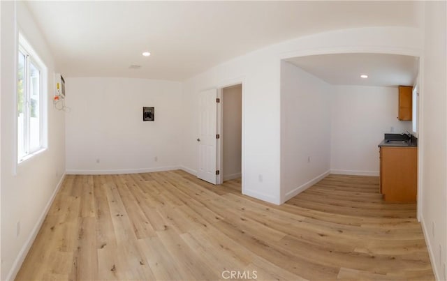 spare room featuring recessed lighting, light wood finished floors, baseboards, and a sink