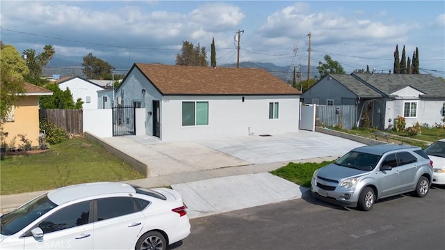 view of front of home with concrete driveway, stucco siding, fence, and a gate