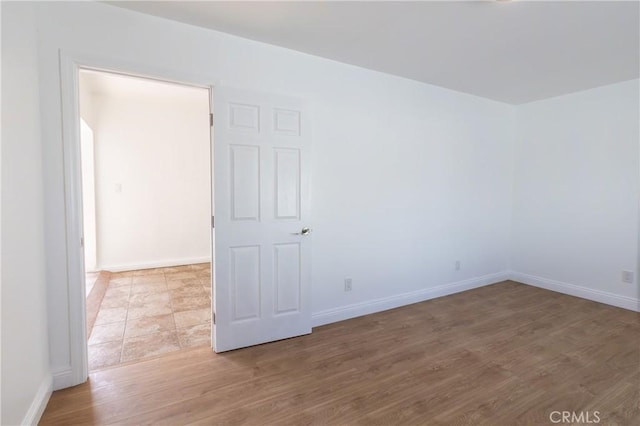 empty room with baseboards and wood finished floors