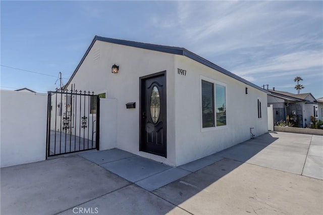 exterior space featuring fence, a patio, a gate, and stucco siding
