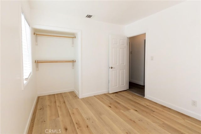 unfurnished bedroom featuring wood finished floors, baseboards, and visible vents
