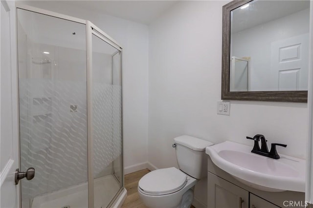 full bathroom featuring vanity, toilet, wood finished floors, a stall shower, and baseboards
