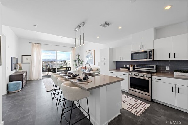 kitchen with visible vents, white cabinets, tasteful backsplash, a sink, and appliances with stainless steel finishes