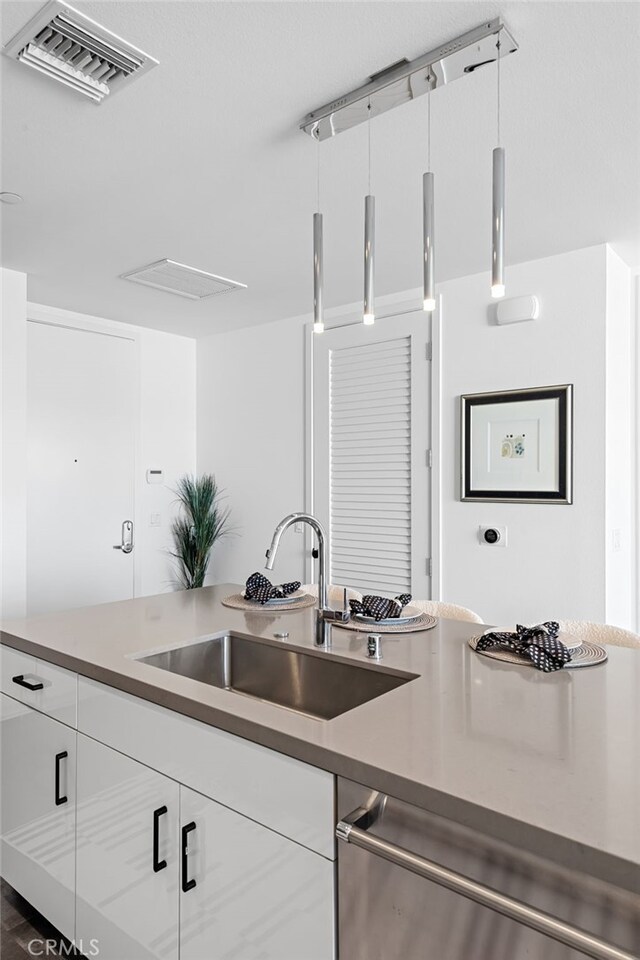 kitchen featuring visible vents, a sink, white cabinetry, and dishwasher