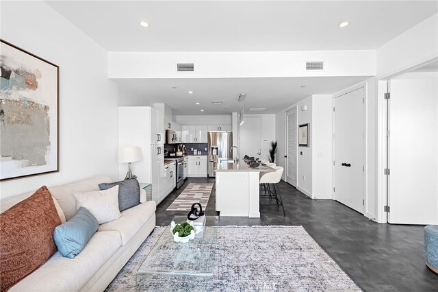 living area featuring concrete flooring, recessed lighting, and visible vents