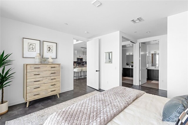 bedroom with visible vents, baseboards, and ensuite bathroom