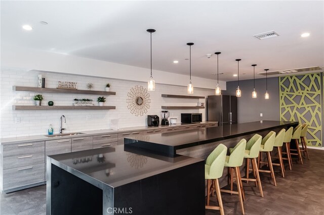 bar featuring visible vents, a sink, freestanding refrigerator, and indoor wet bar