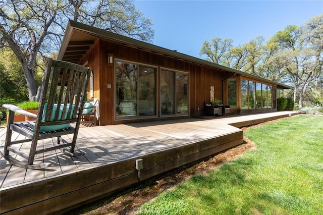back of house featuring board and batten siding, a deck, and a yard