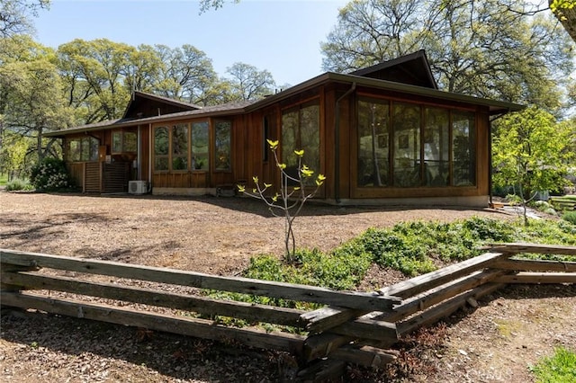 view of side of home with fence and a sunroom